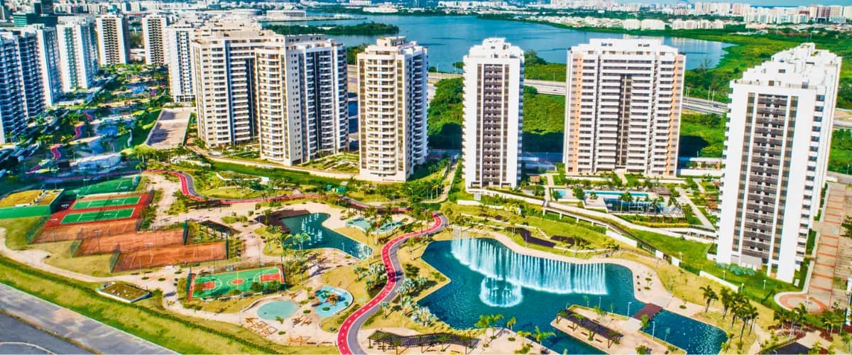 Home 10 Vista aérea do Ilha Pura na Barra da Tijuca com lago, quadras esportivas, áreas de lazer e condomínios residenciais.